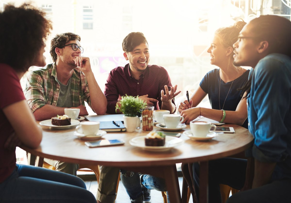 Group of friends talking together around a table in a cafe